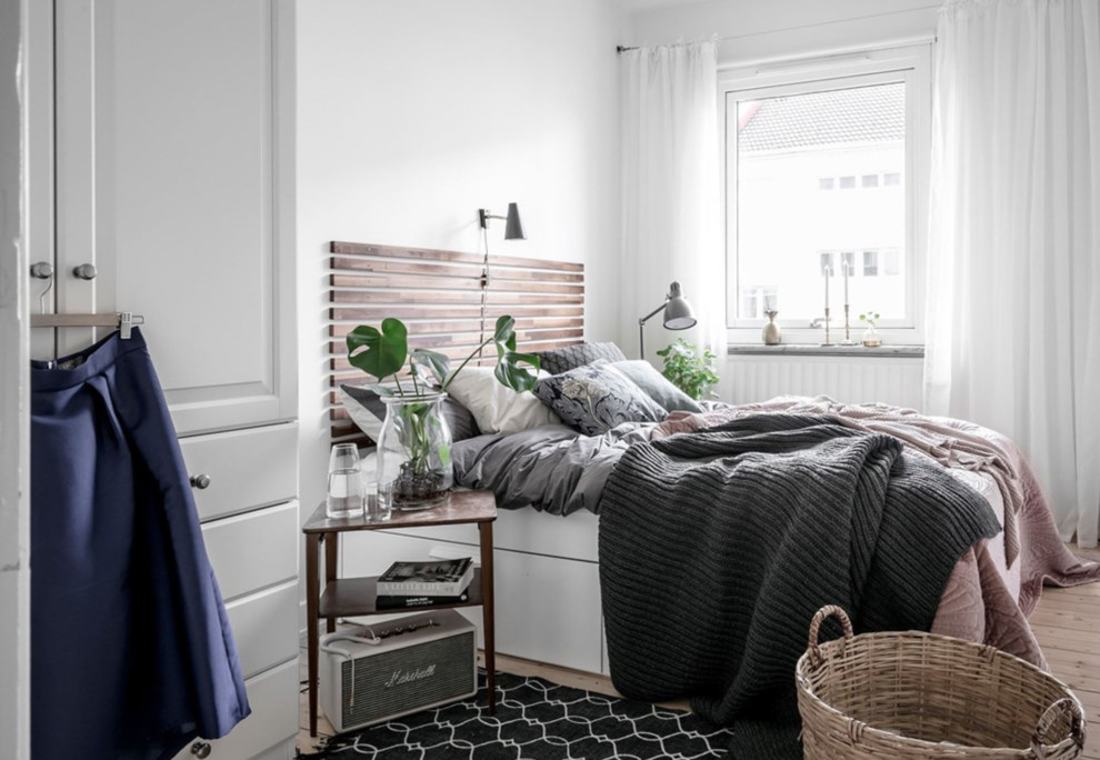 Immagine di una camera matrimoniale scandinava con pareti bianche e parquet chiaro
