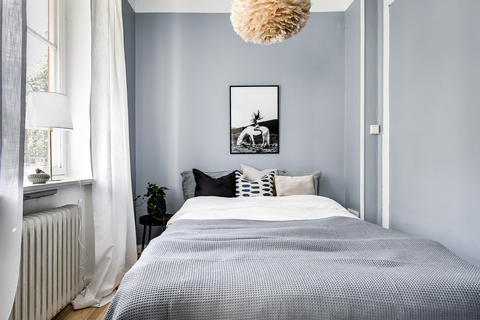 Inredning av ett minimalistiskt litet sovrum, med grå väggar, ljust trägolv och beiget golv