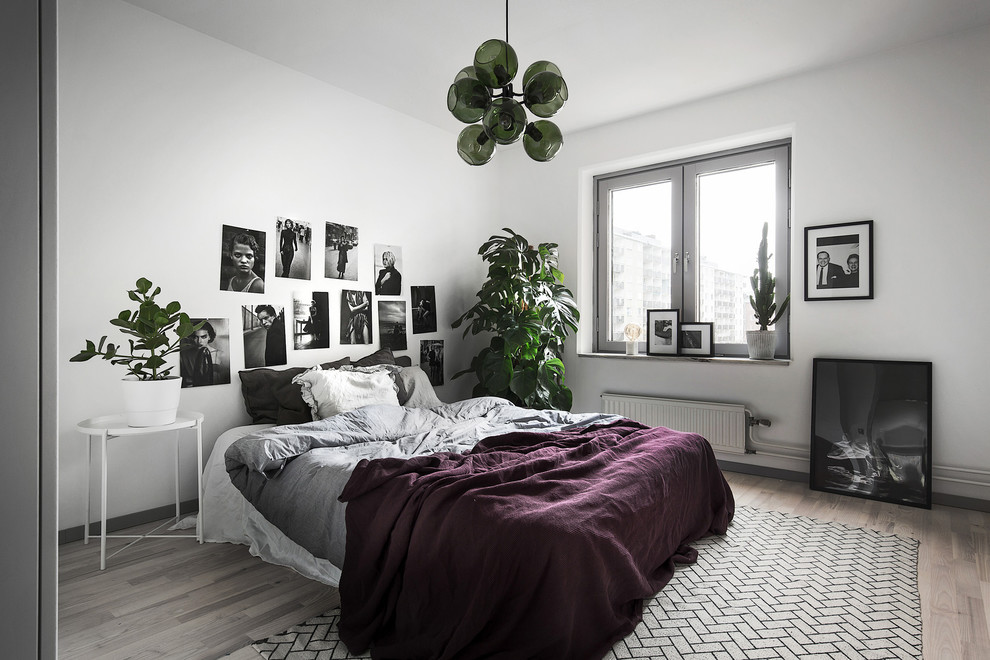 Diseño de dormitorio principal escandinavo de tamaño medio sin chimenea con paredes grises y suelo de madera clara