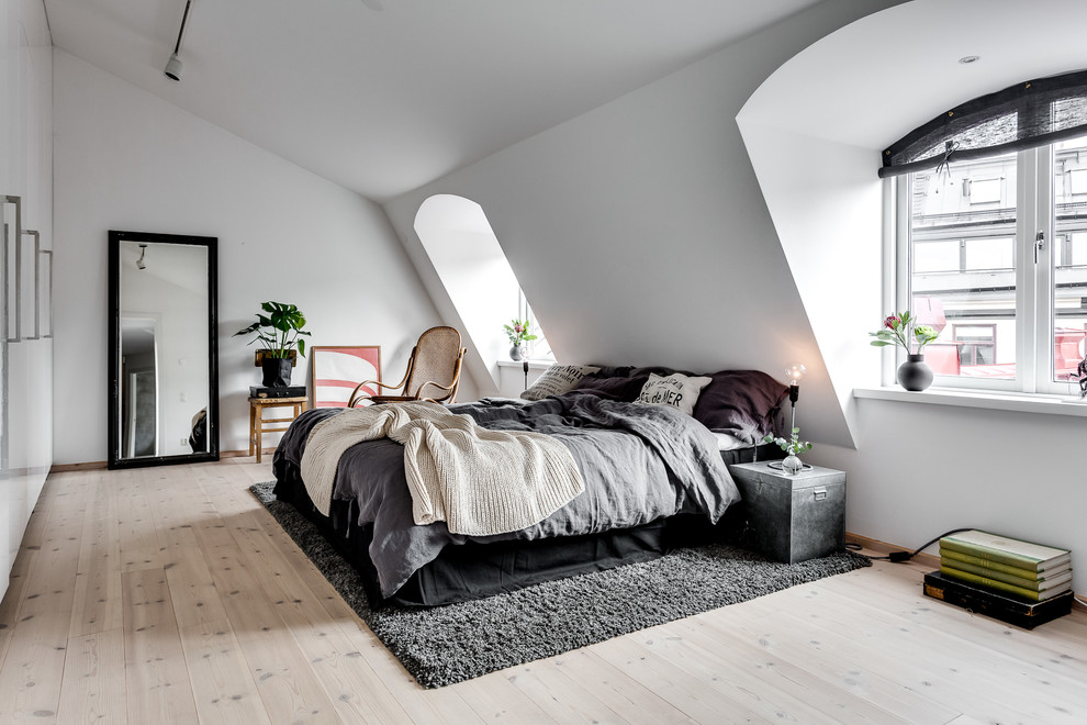 ストックホルムにある広い北欧スタイルのおしゃれな主寝室 (白い壁、淡色無垢フローリング、暖炉なし、ベッド下のラグ)