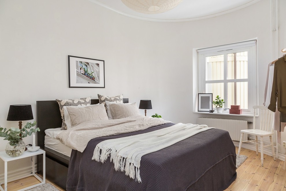 Foto på ett minimalistiskt sovrum, med mellanmörkt trägolv