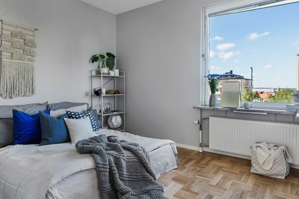 На фото: гостевая спальня (комната для гостей) в скандинавском стиле с серыми стенами, светлым паркетным полом и бежевым полом с