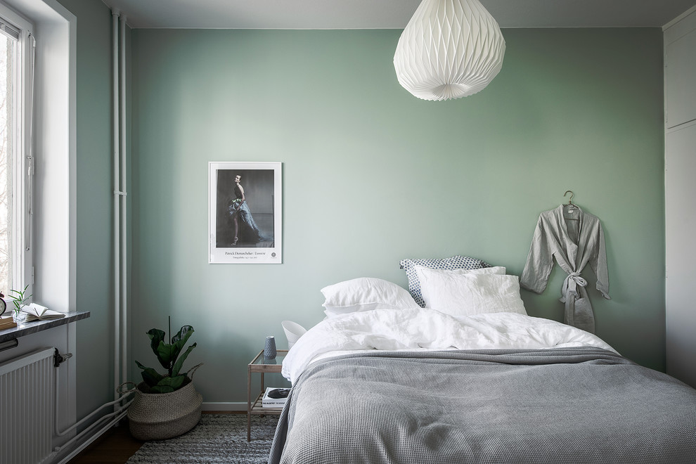 This is an example of a scandi master bedroom in Stockholm with green walls.