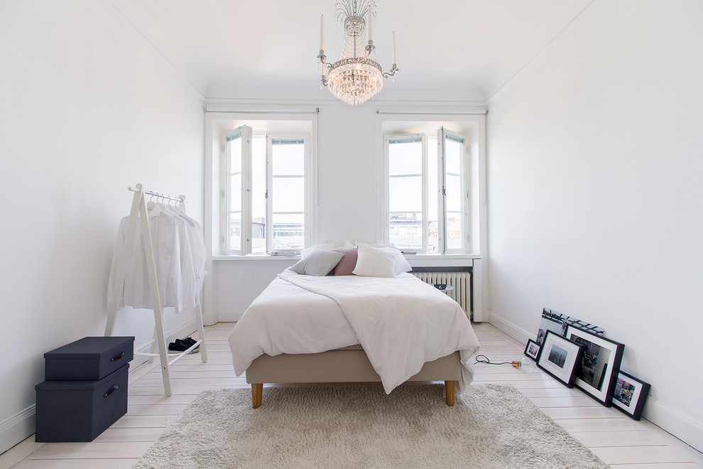На фото: спальня среднего размера в скандинавском стиле с белыми стенами и светлым паркетным полом без камина с