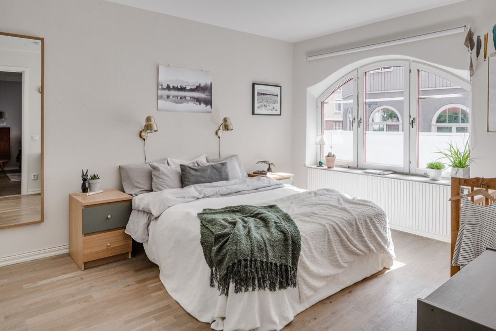 This is an example of a medium sized scandi master bedroom in Gothenburg with grey walls and light hardwood flooring.