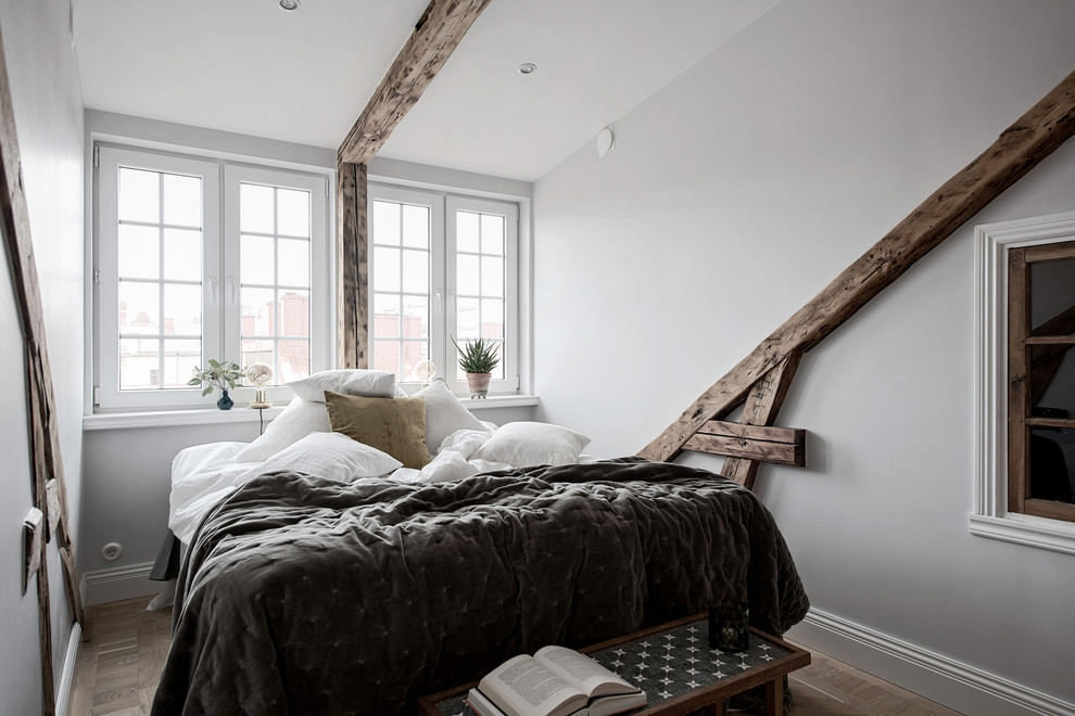 Réalisation d'une petite chambre parentale nordique avec un mur blanc, un sol en bois brun et un sol marron.