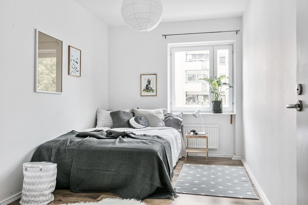 Modelo de dormitorio escandinavo con paredes blancas, suelo de madera oscura y suelo marrón