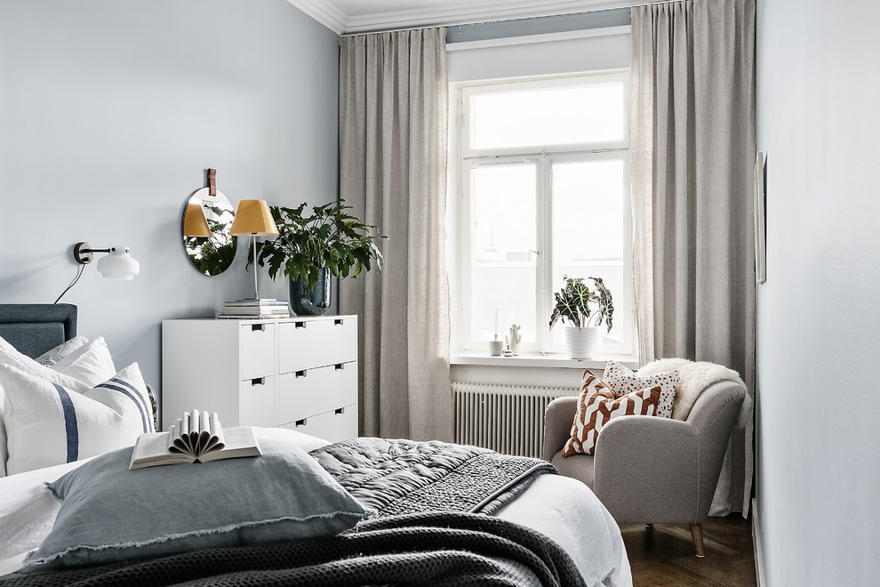 Diseño de habitación de invitados escandinava sin chimenea con paredes grises, suelo de madera en tonos medios y suelo marrón