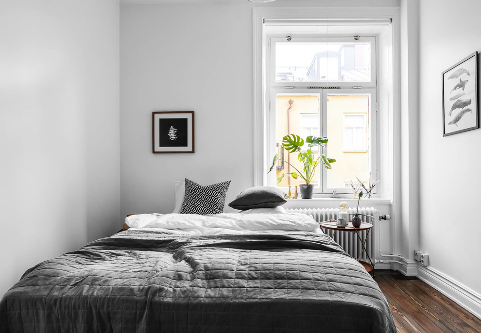 Photo of a scandinavian bedroom in Stockholm with white walls, dark hardwood flooring and brown floors.