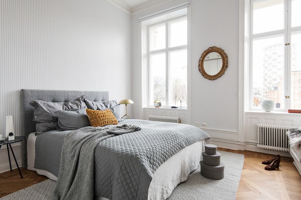 Idée de décoration pour une chambre parentale nordique avec un mur blanc, aucune cheminée et un sol en bois brun.