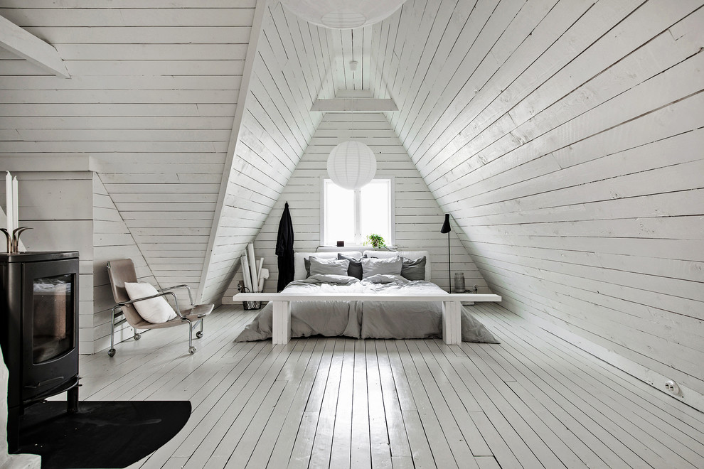 ヨーテボリにある中くらいな北欧スタイルのおしゃれな寝室 (白い壁、塗装フローリング、白い床、薪ストーブ、勾配天井)