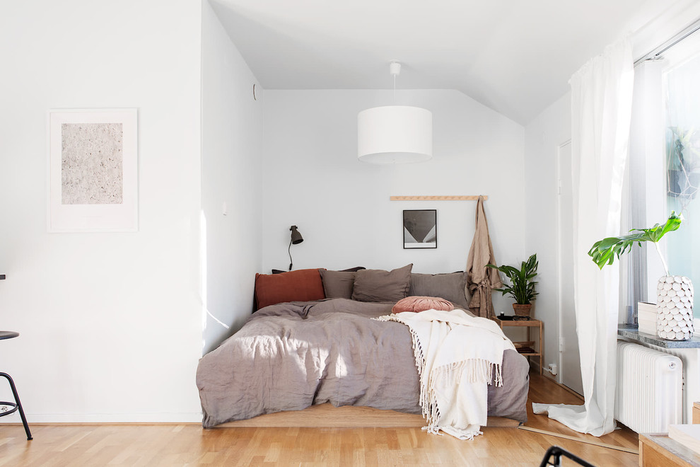 На фото: маленькая хозяйская спальня в скандинавском стиле с белыми стенами, светлым паркетным полом и бежевым полом для на участке и в саду