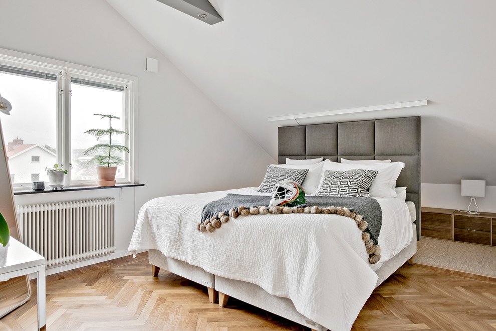 Modelo de habitación de invitados escandinava de tamaño medio con paredes blancas y suelo de madera en tonos medios