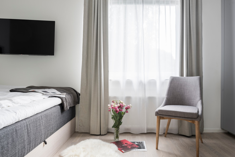 Imagen de dormitorio nórdico de tamaño medio con paredes beige y suelo de madera clara