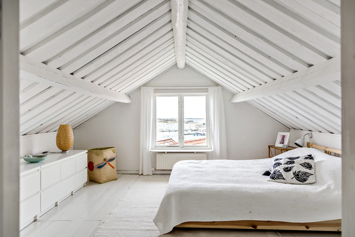 Coastal loft bedroom in Gothenburg with white walls, light hardwood flooring and white floors.