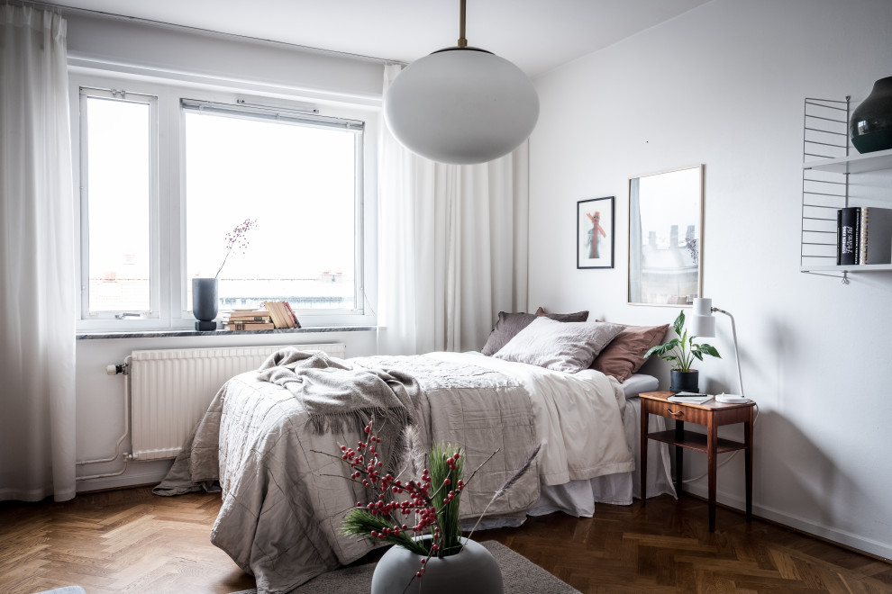 Foto di una camera da letto scandinava con pareti bianche, parquet scuro e pavimento marrone