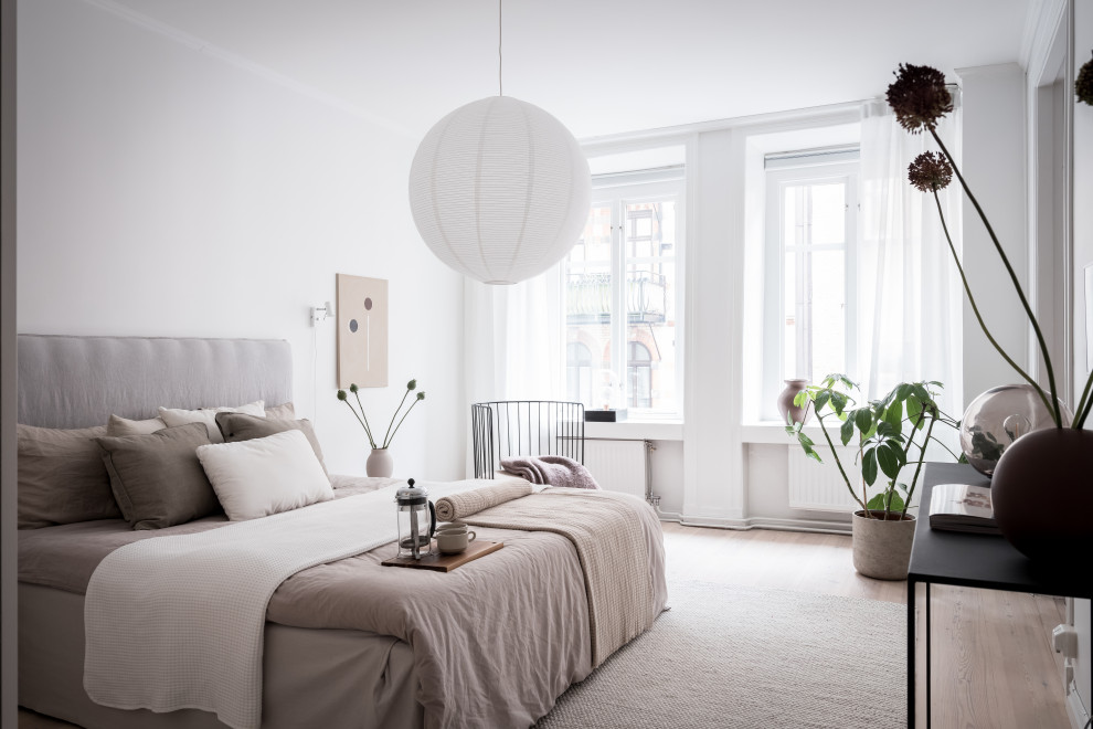 Foto de dormitorio escandinavo con paredes blancas, suelo de madera clara y suelo beige