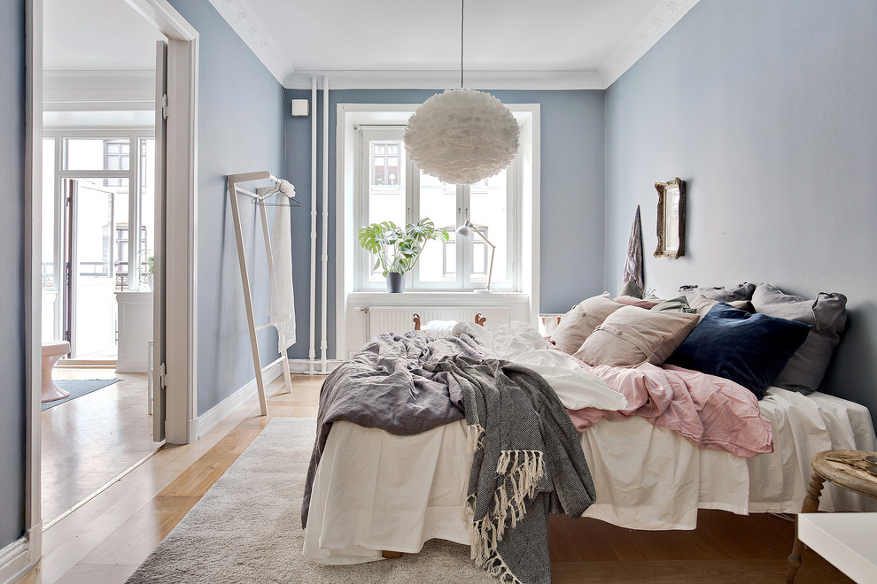 Réalisation d'une chambre parentale nordique de taille moyenne avec un mur bleu et parquet clair.