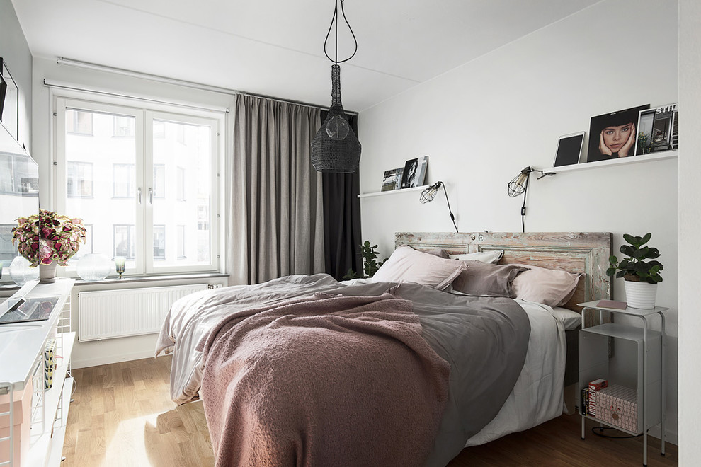 This is an example of a large modern master bedroom in Stockholm with white walls, light hardwood flooring and no fireplace.
