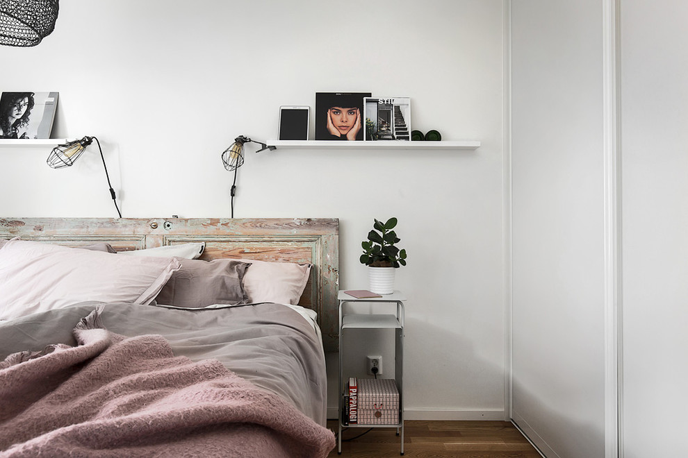 Modelo de dormitorio principal escandinavo de tamaño medio con paredes blancas y suelo de madera en tonos medios