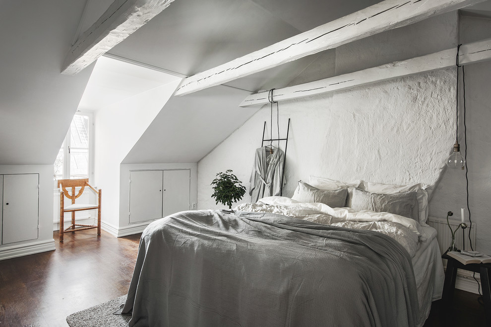 Modelo de dormitorio nórdico de tamaño medio sin chimenea con paredes blancas, suelo de madera oscura y suelo marrón