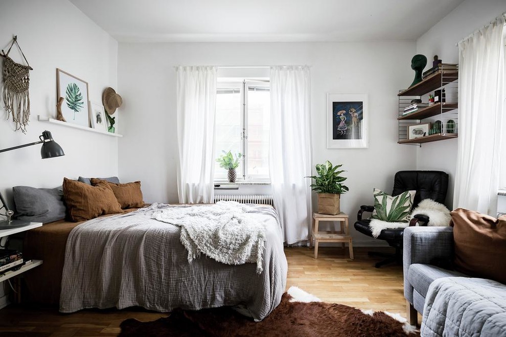 Idéer för att renovera ett litet nordiskt sovrum, med vita väggar, ljust trägolv och brunt golv