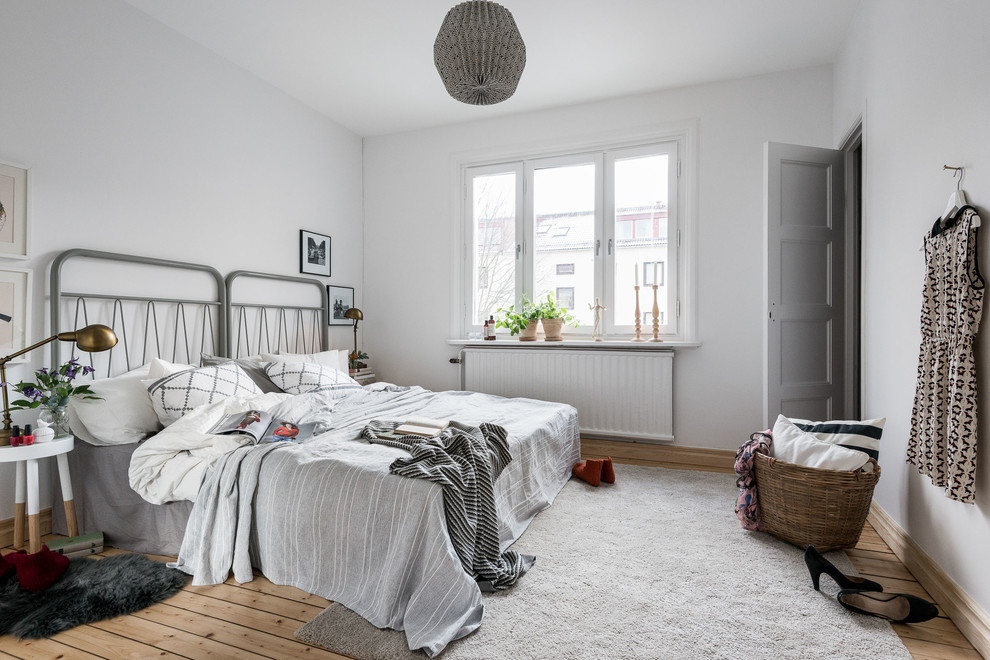 Medium sized scandinavian master bedroom in Gothenburg with white walls and light hardwood flooring.