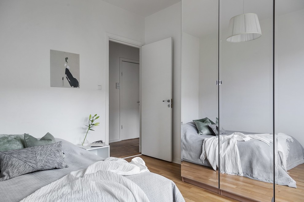 Inspiration för minimalistiska sovrum, med vita väggar, mellanmörkt trägolv och brunt golv