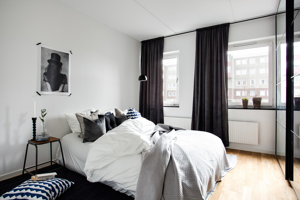 Scandinavian master bedroom in Other with white walls, light hardwood flooring and no fireplace.