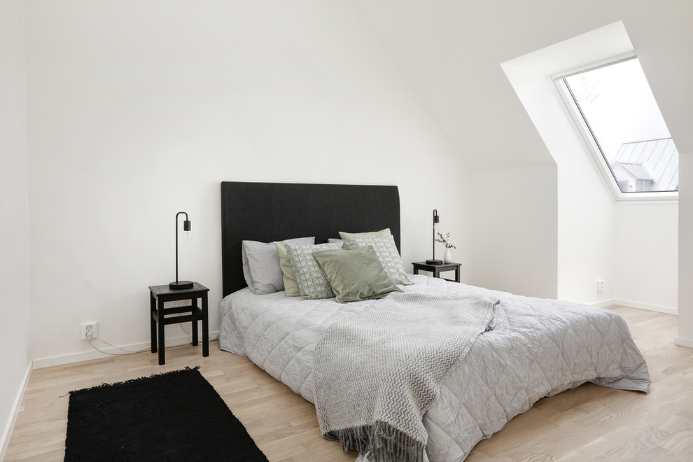Modelo de dormitorio escandinavo con paredes blancas y suelo de madera en tonos medios