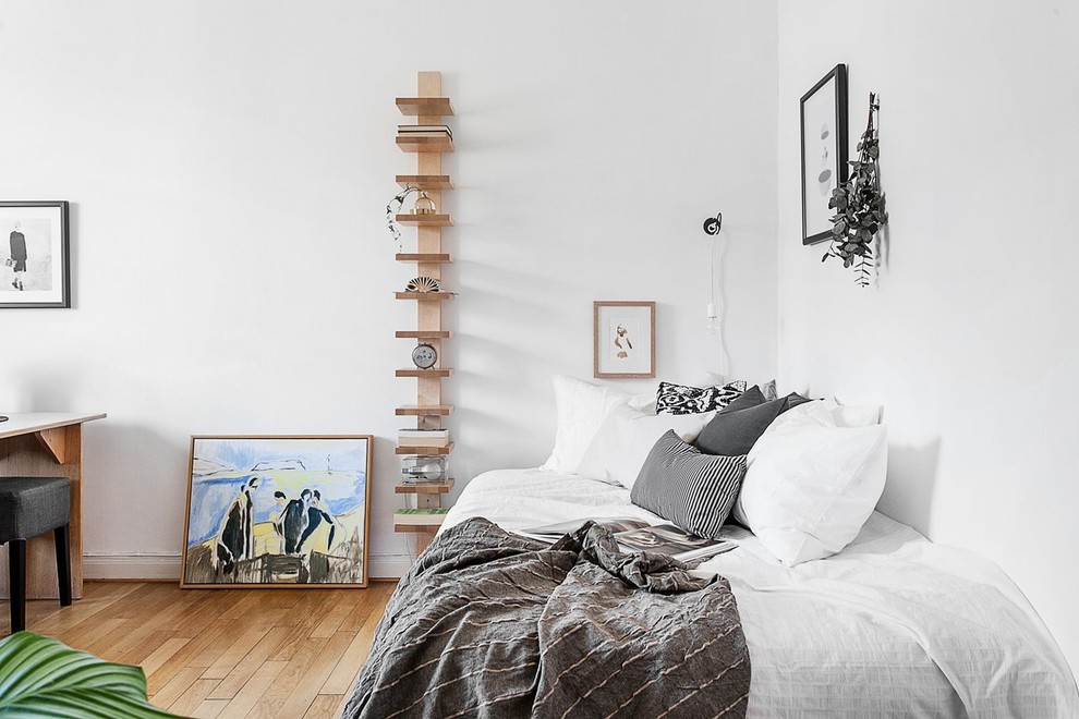 Esempio di una camera degli ospiti scandinava di medie dimensioni con pareti bianche, pavimento in legno massello medio e nessun camino