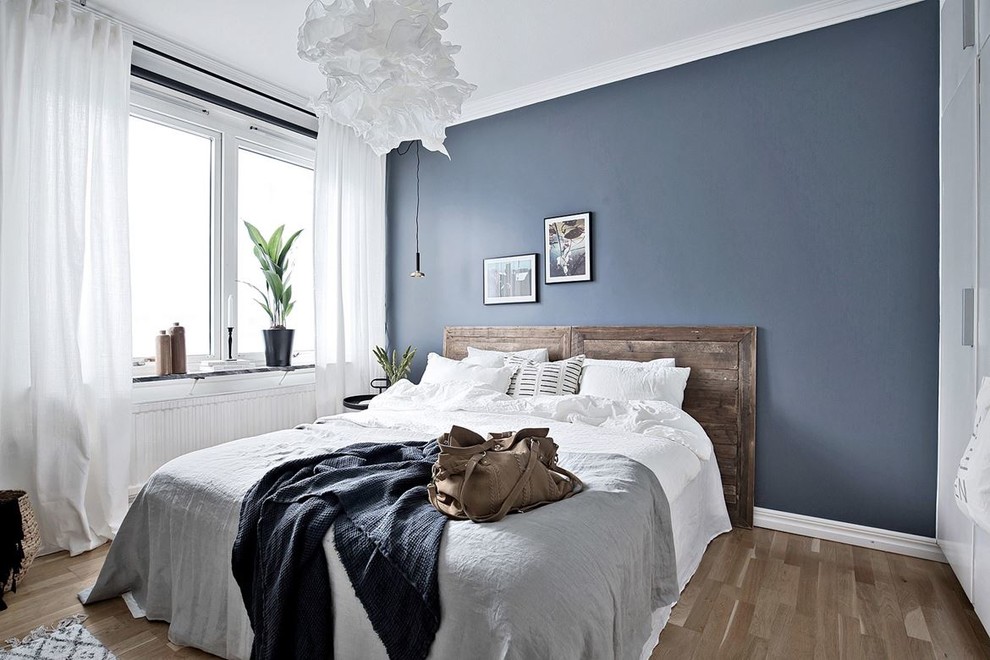 ヨーテボリにある中くらいな北欧スタイルのおしゃれな主寝室 (青い壁、無垢フローリング)