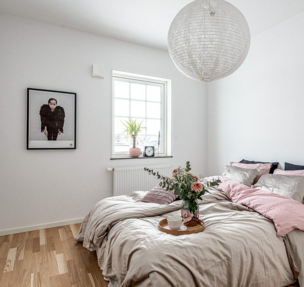 Стильный дизайн: гостевая спальня (комната для гостей) в скандинавском стиле с белыми стенами, полом из ламината и бежевым полом - последний тренд