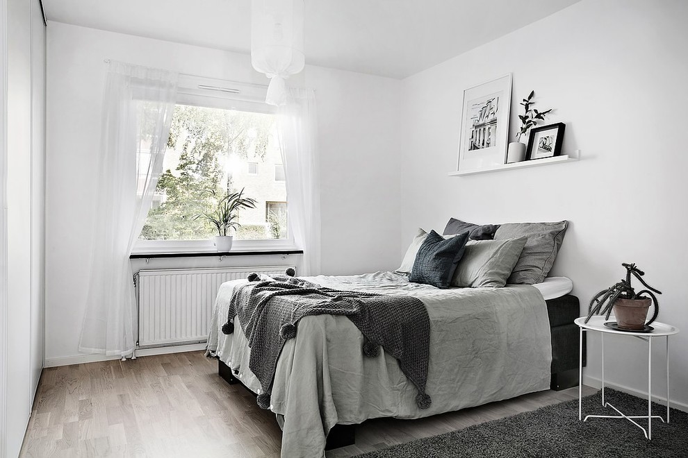 Großes Nordisches Hauptschlafzimmer mit weißer Wandfarbe und hellem Holzboden in Göteborg