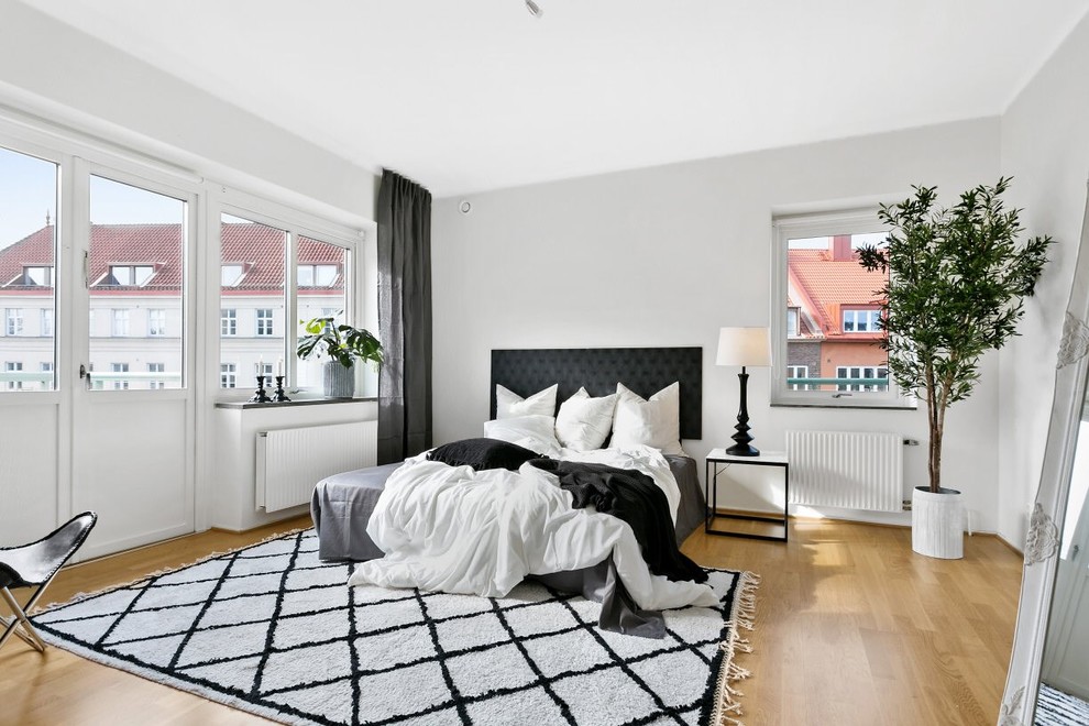 Idéer för att renovera ett minimalistiskt sovrum, med vita väggar, ljust trägolv och beiget golv