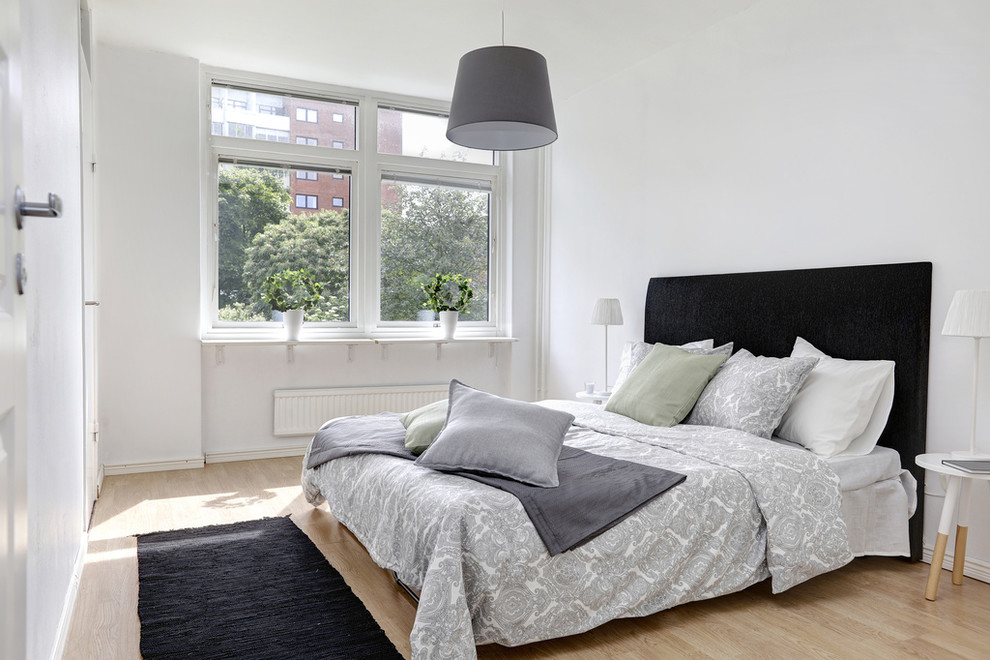 Idéer för skandinaviska sovrum, med vita väggar och mellanmörkt trägolv