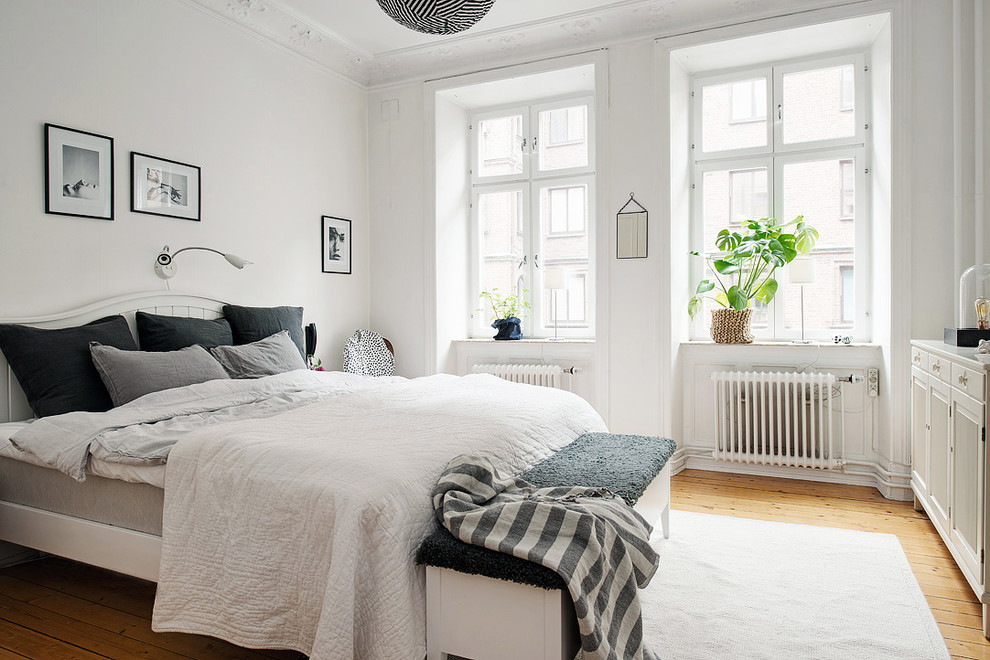 Inspiration for a medium sized scandi master bedroom in Gothenburg with white walls, light hardwood flooring and no fireplace.
