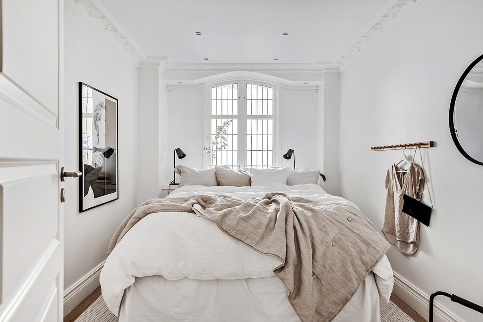 Esempio di una piccola camera matrimoniale scandinava con pareti bianche, parquet scuro e pavimento marrone