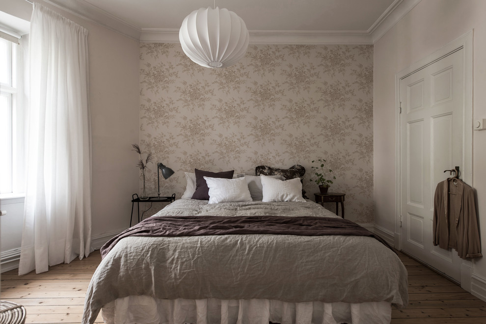 Immagine di una camera matrimoniale nordica con pareti beige, pavimento in legno massello medio e pavimento beige