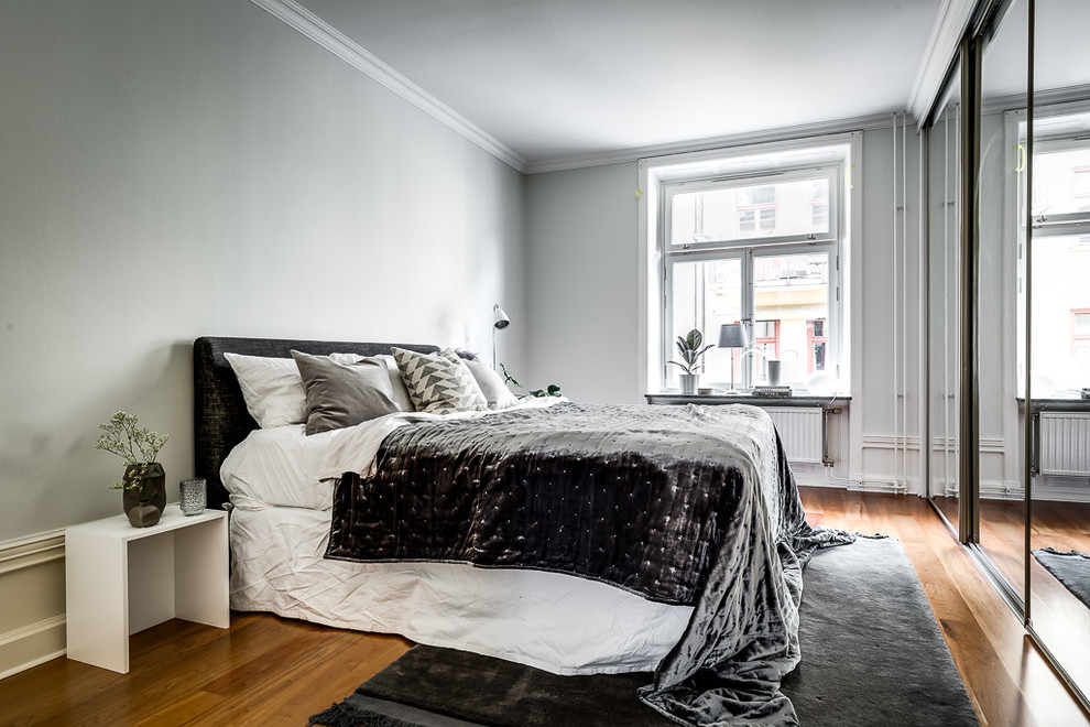 ストックホルムにある北欧スタイルのおしゃれな寝室 (グレーの壁、無垢フローリング、茶色い床、グレーとブラウン) のインテリア