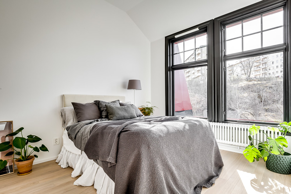 Imagen de dormitorio principal escandinavo de tamaño medio con paredes blancas, suelo laminado y suelo beige