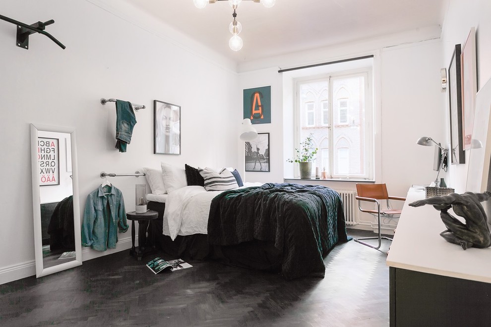 This is an example of a large scandi bedroom in Stockholm with white walls, plywood flooring, no fireplace and black floors.