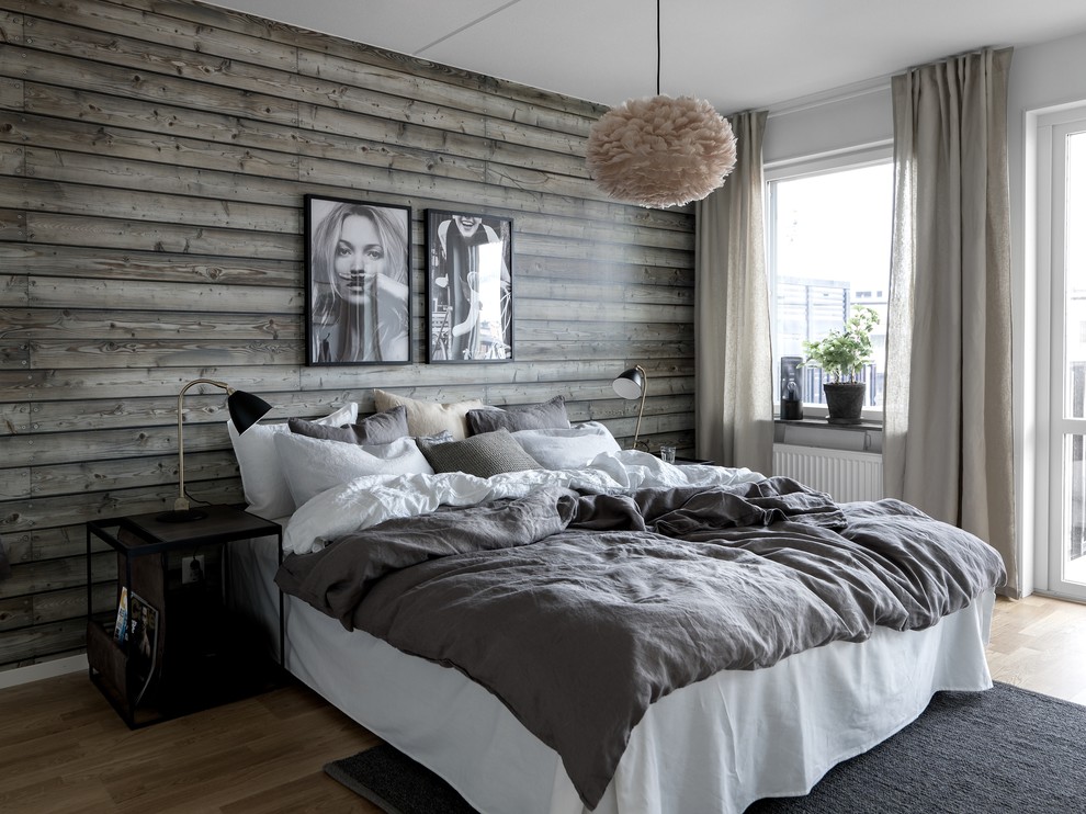 This is an example of a large scandinavian master bedroom in Stockholm with white walls, light hardwood flooring, no fireplace and brown floors.