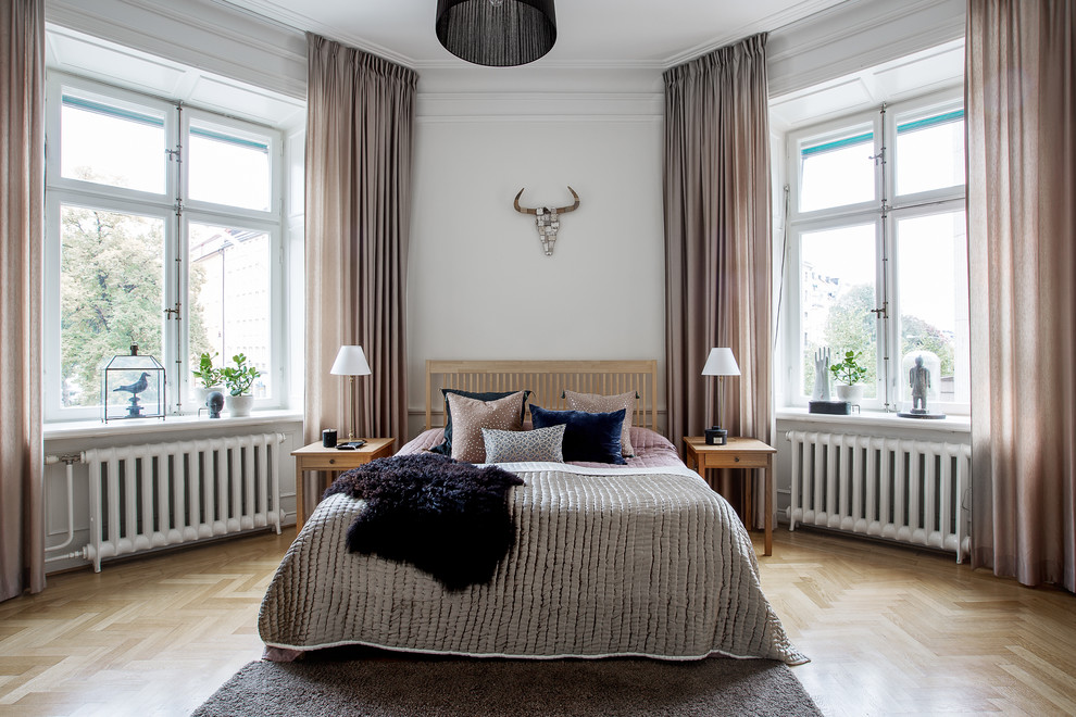 На фото: большая хозяйская спальня в скандинавском стиле с белыми стенами и светлым паркетным полом