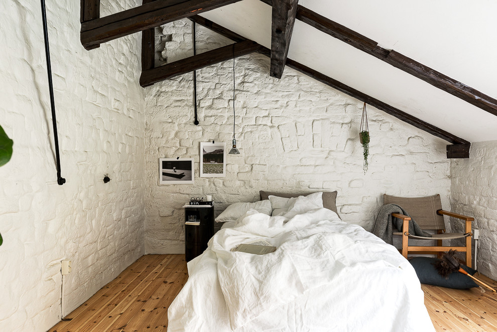 Cette image montre une chambre parentale chalet de taille moyenne avec un mur blanc et un sol en bois brun.