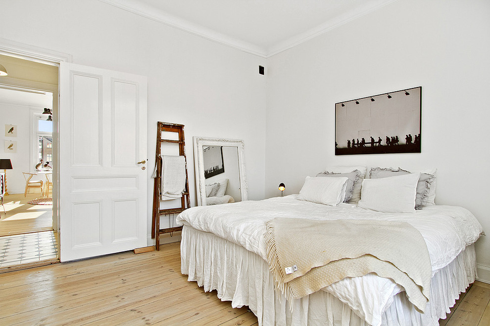This is an example of a large romantic bedroom in Stockholm with white walls and light hardwood flooring.