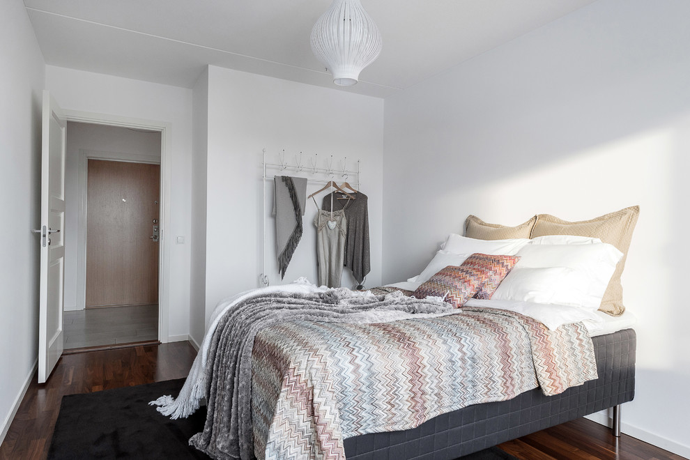Imagen de dormitorio nórdico con paredes blancas y suelo marrón