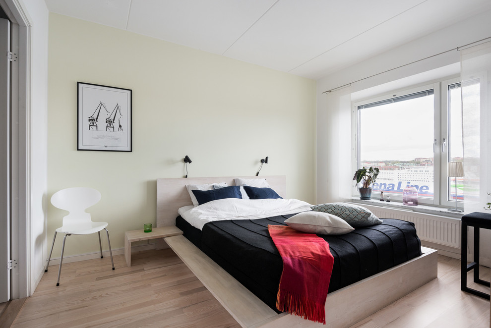 Photo of a medium sized scandi master bedroom in Gothenburg with yellow walls, light hardwood flooring and beige floors.
