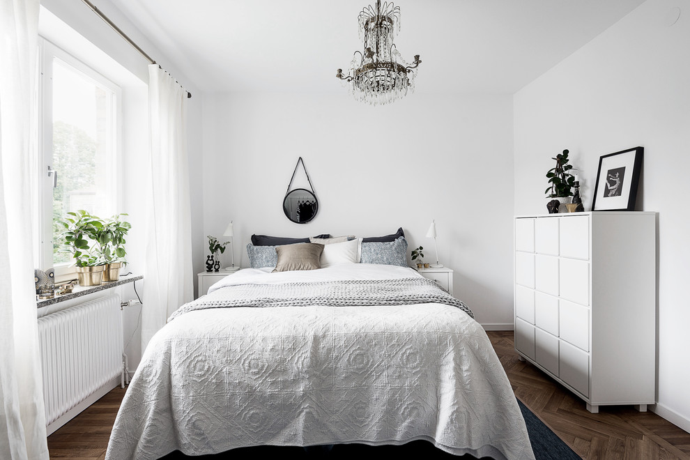 This is an example of a medium sized scandinavian master bedroom in Gothenburg with white walls, medium hardwood flooring and brown floors.