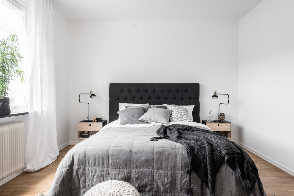 Mittelgroßes Skandinavisches Hauptschlafzimmer mit weißer Wandfarbe und braunem Holzboden in Göteborg